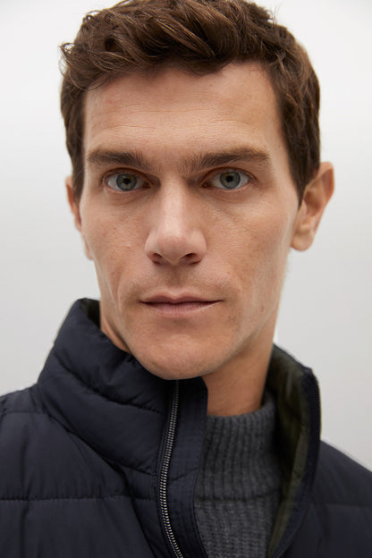 Men's dark navy puffer jacket close-up, quilted texture with full zipper