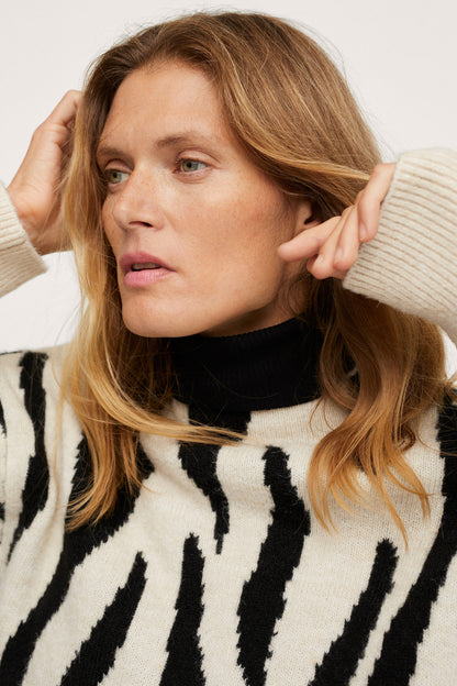 Close-up of zebra-striped knit sweater with ribbed neckline and long sleeves