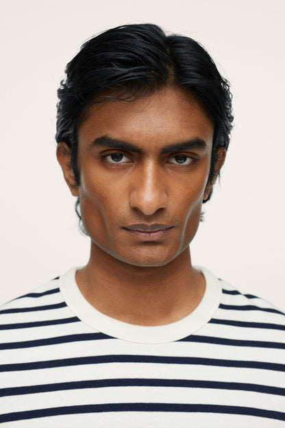 Off-white crewneck top with navy horizontal stripes, close-up