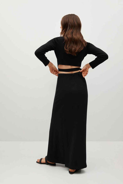 Black long-sleeve crop top and flowing maxi skirt with back cutout and side slit