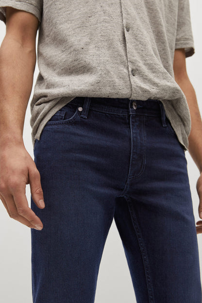 Dark blue denim jeans close-up, button fly, stitched seams, belt loops