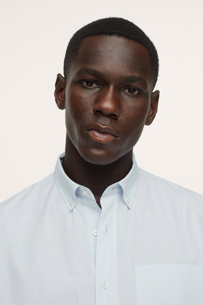 Men's light blue button-up shirt with spread collar, close-up