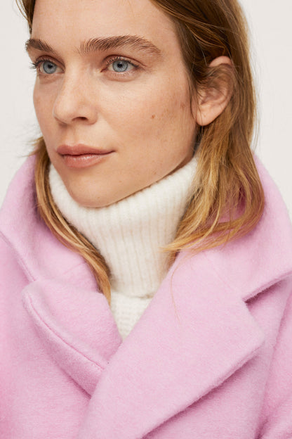 Close-up of pale pink coat lapels with white ribbed turtleneck underneath