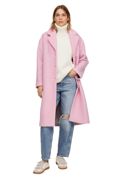 Pale pink long coat with lapel collar and button front, worn over knit sweater