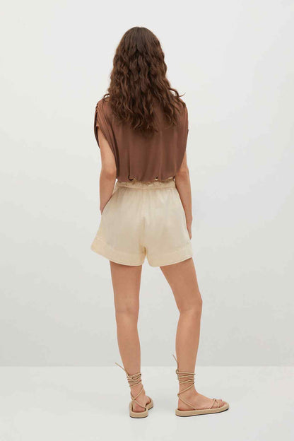 Brown short-sleeve top with round back and cream shorts