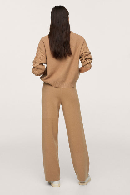 Tan knit turtleneck sweater and wide-leg trousers, back view