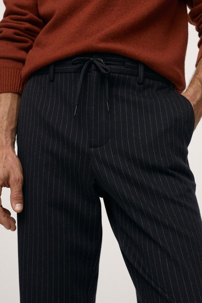 Dark navy pinstripe trousers close-up: drawstring waist and front pleats