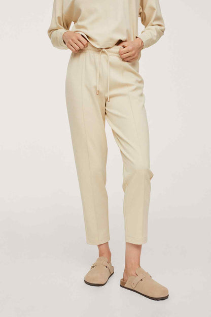 Ecru tapered pants with drawstring waist, side pockets, ankle cuffs