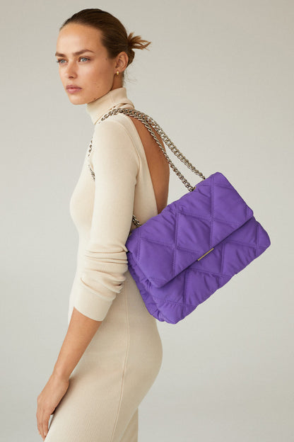 Purple quilted shoulder bag worn crossbody, chain strap and flap