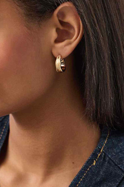 Gold textured hoop earrings with small oval huggie shape