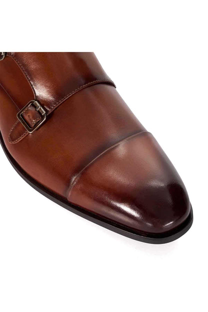 Dune London dark tan leather shoe close-up, metal buckle strap and stitched panel