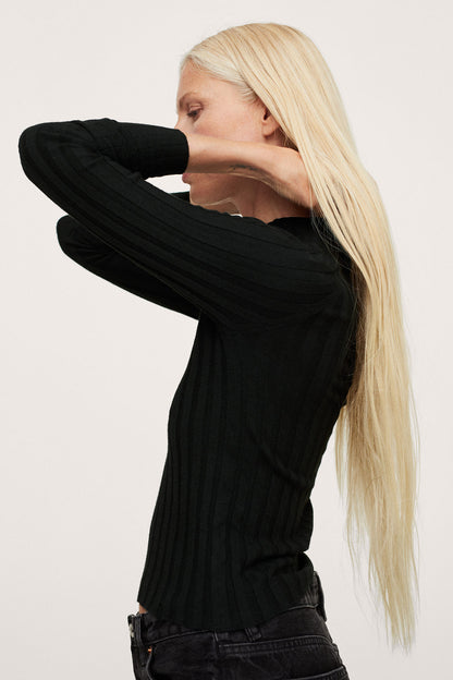 Black ribbed turtleneck sweater with black denim jeans, folded-arm close-up