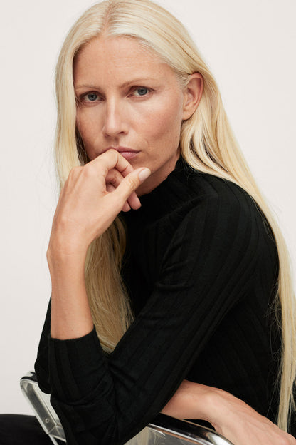 Black ribbed turtleneck sweater, high neck detail, close-up portrait