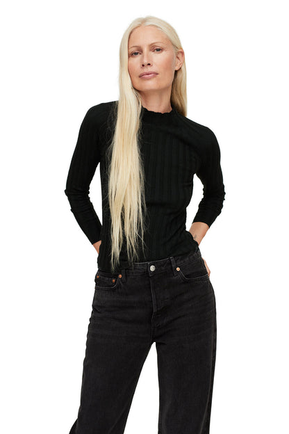 Black ribbed turtleneck sweater and black denim jeans, front view