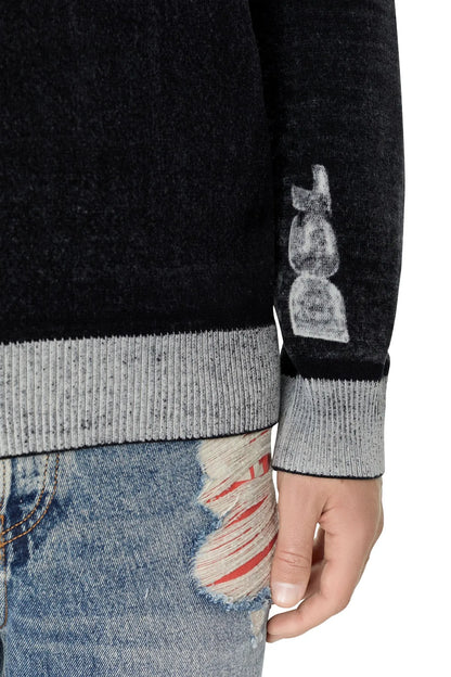 Black sweater sleeve close-up with gray ribbed cuff and gray graphic print