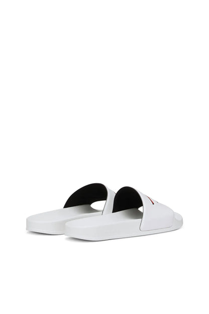 White slide sandals with black lining under the wide logo strap