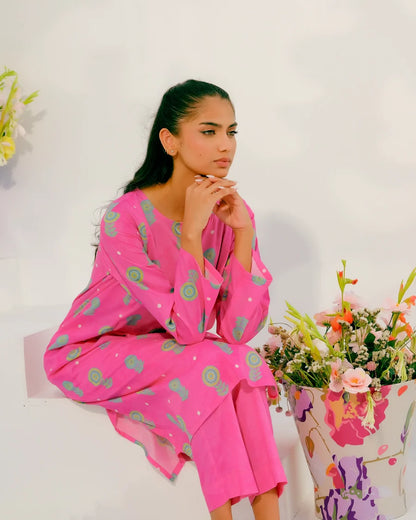 Women's pink printed kurta with long sleeves and matching pants, sitting pose