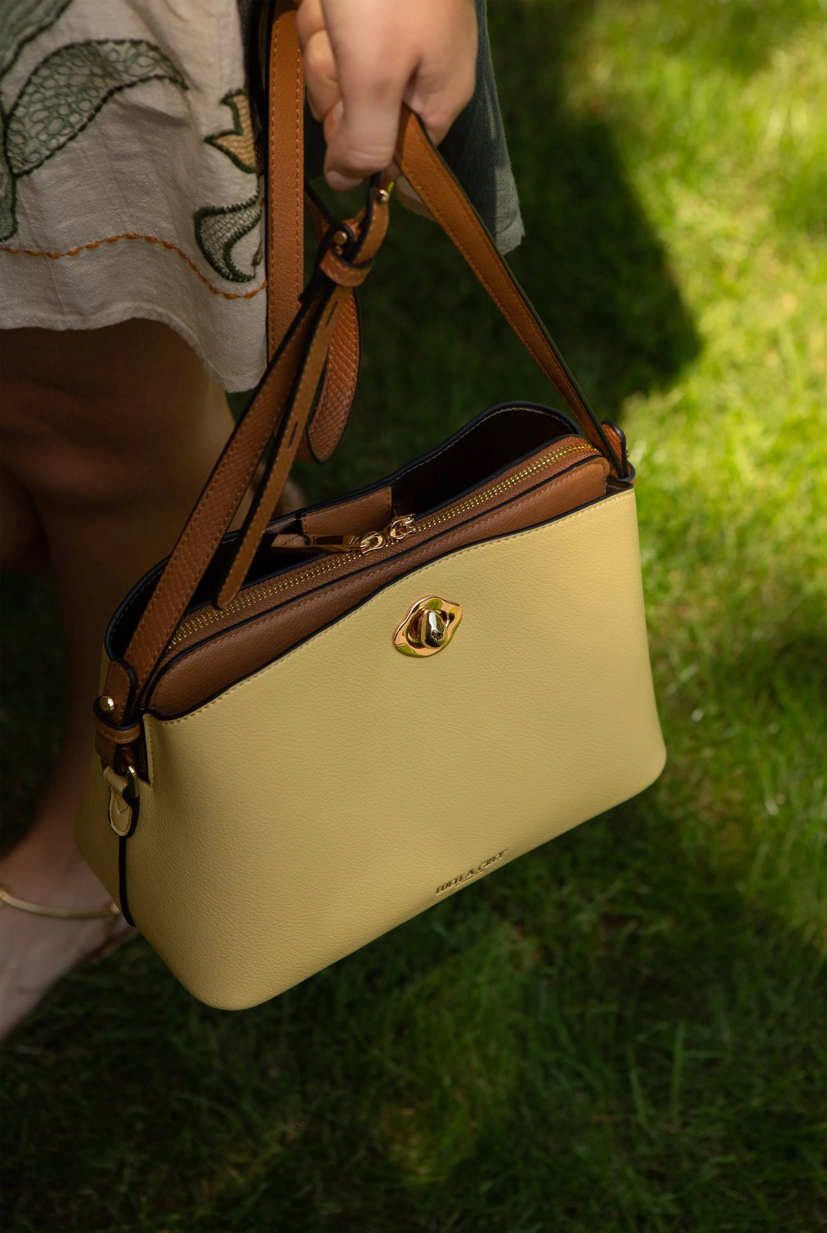 Yellow mini bag close-up with gold zipper pull and brown leather straps