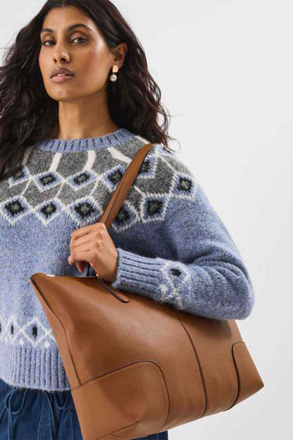 Tan leather-look tote bag with top handles and side seams, held on model