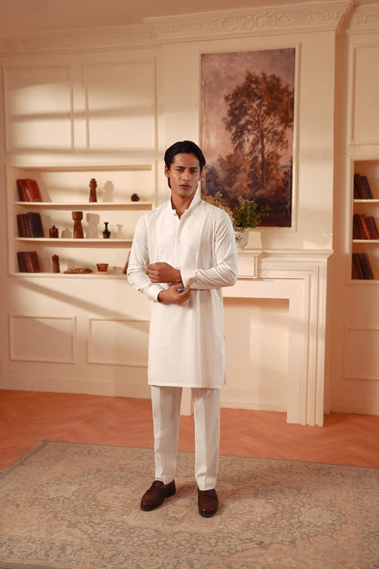 Men's white kurta and pants set, standing pose with hands clasped