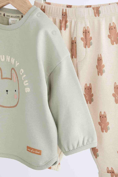 Sage green long-sleeve top with bunny graphic and cream bunny print shorts, side view