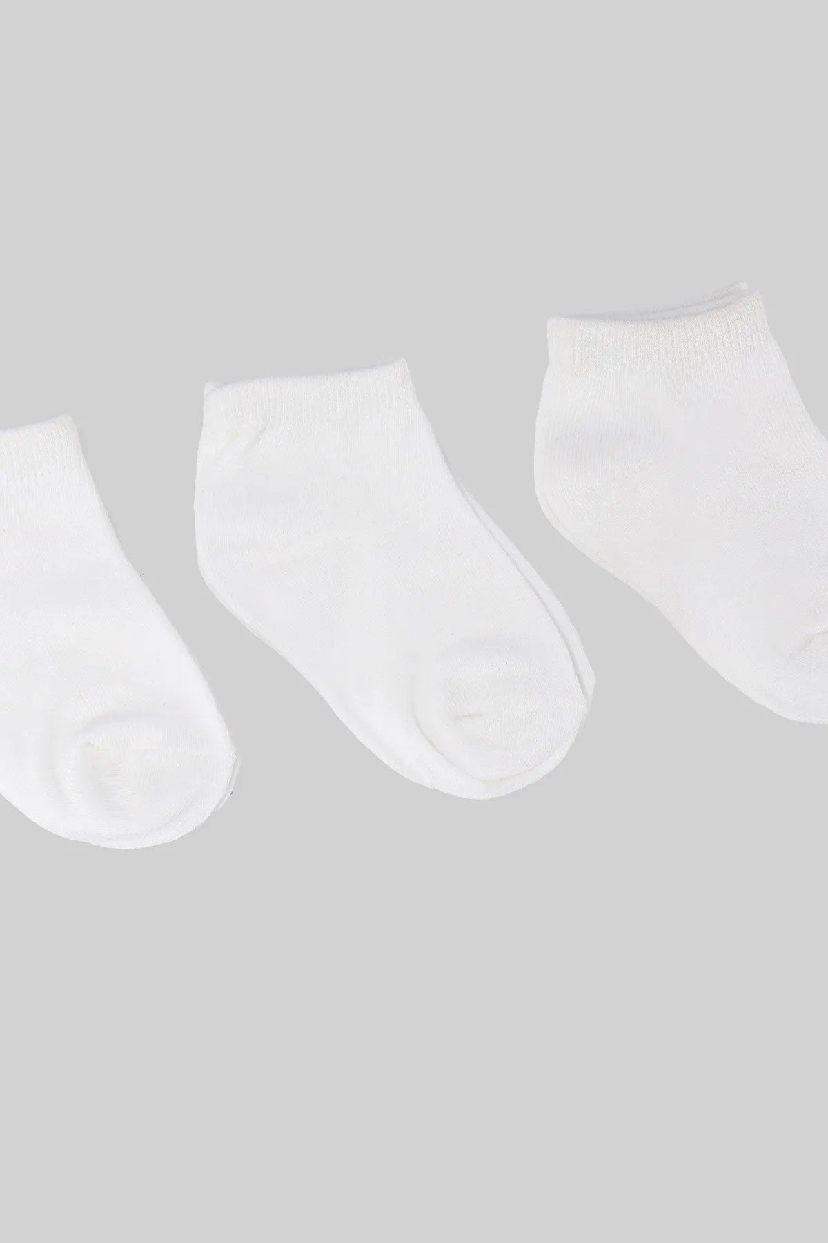 Three white baby socks, ribbed cuffs, smooth knit and rounded toe