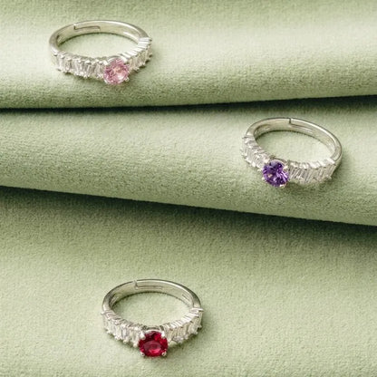 Set of three silver-tone rings with pink, purple, and red gemstones