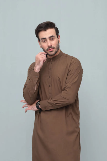Men's brown long kurta with matching shalwar, front pose with hand near chin