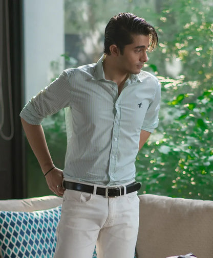 Men's fitted striped button-up shirt with white pants and black belt, standing