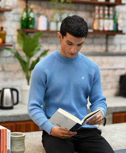 Fitted blue knit sweater with ribbed crew neck, looking down and reading