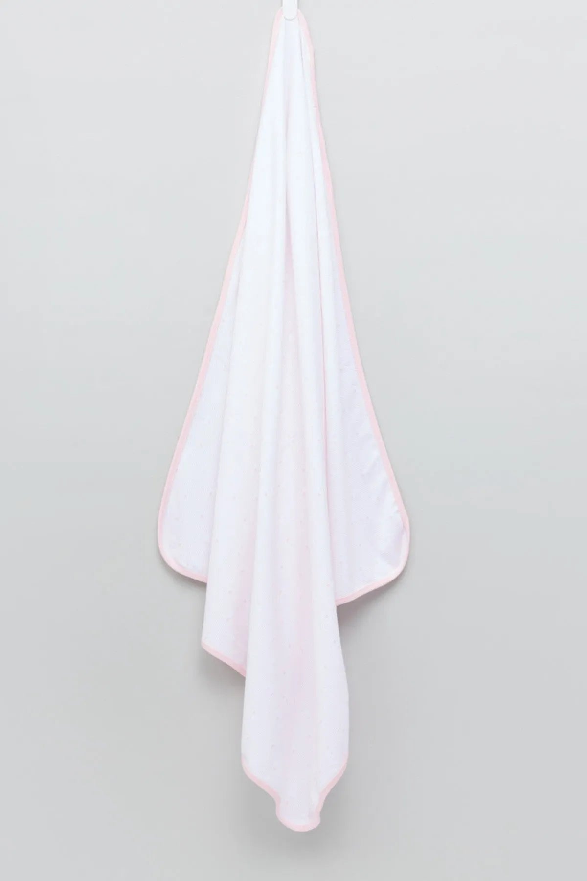 Light pink baby blanket draped with soft stitched border