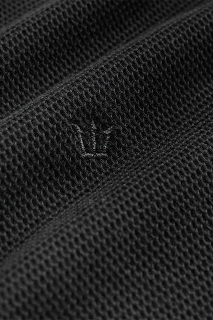 Black textured polo fabric with small embroidered logo on chest