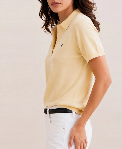 Cream polo shirt with short sleeves, button collar, small logo on left chest
