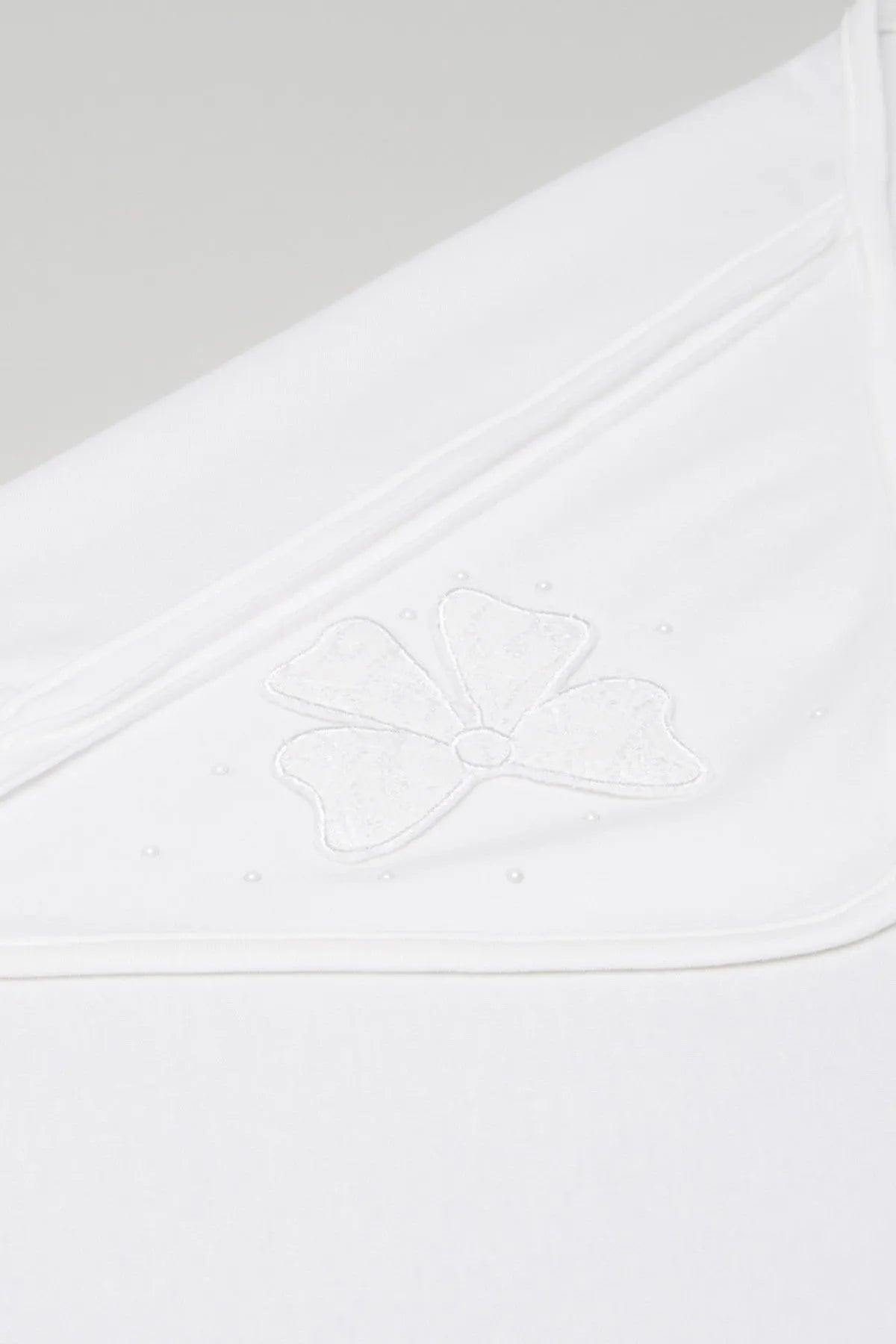 White baby blanket close-up of embroidered floral applique on corner