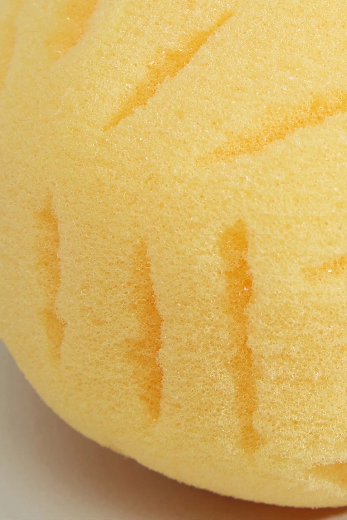 Close-up of yellow bath sponge with embossed stripe ridges