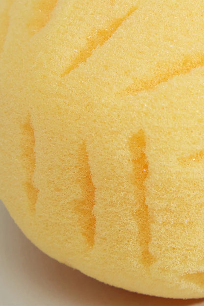 Close-up of yellow bath sponge with embossed stripe ridges