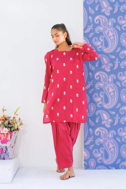 Pink printed kurta with round neck and matching pants, hand adjusting shoulder.