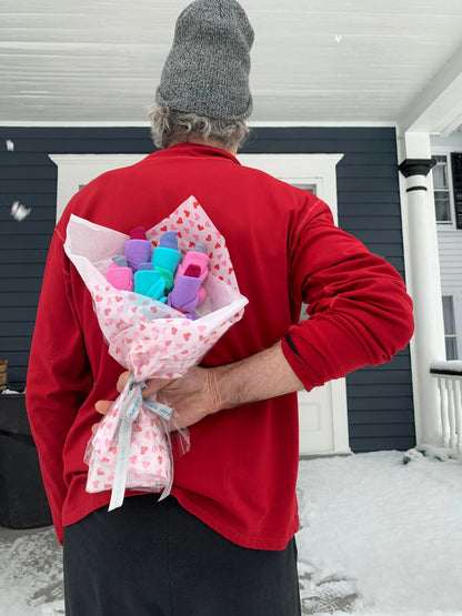 Red-wrapped plush toy bouquet with pink ribbon, held in front of a person