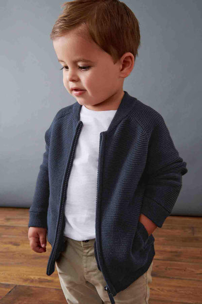 Navy zip-up knit jacket worn by a child, front zipper and side pockets visible