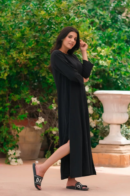 Black long-sleeve maxi dress with round neck and side slit, side view