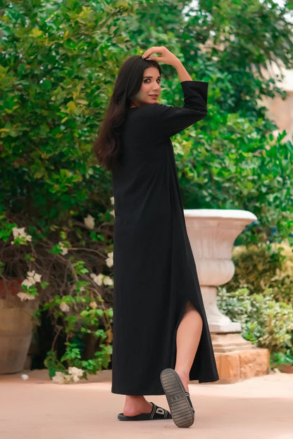 Black long-sleeve maxi dress with round neck and side slit, walking view