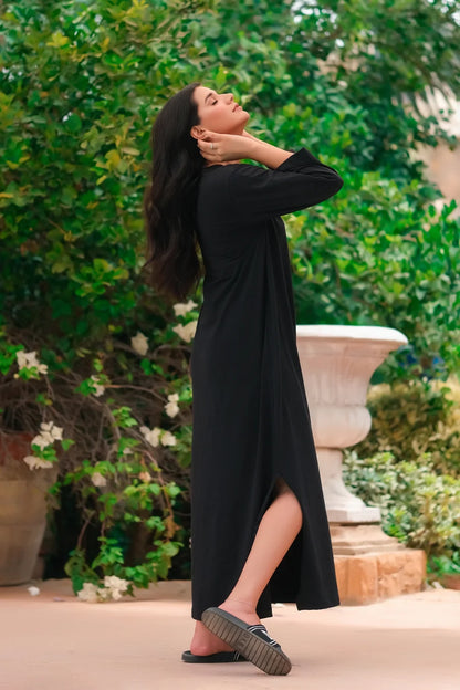 Black long-sleeve maxi dress with round neck and side slit, model in motion