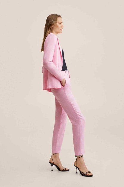 Pink trousers worn with heels, featuring a tailored slim leg and front pleats
