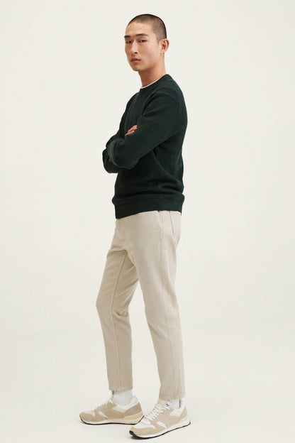 Men's dark green crewneck sweatshirt on model, long sleeves and ribbed cuffs.