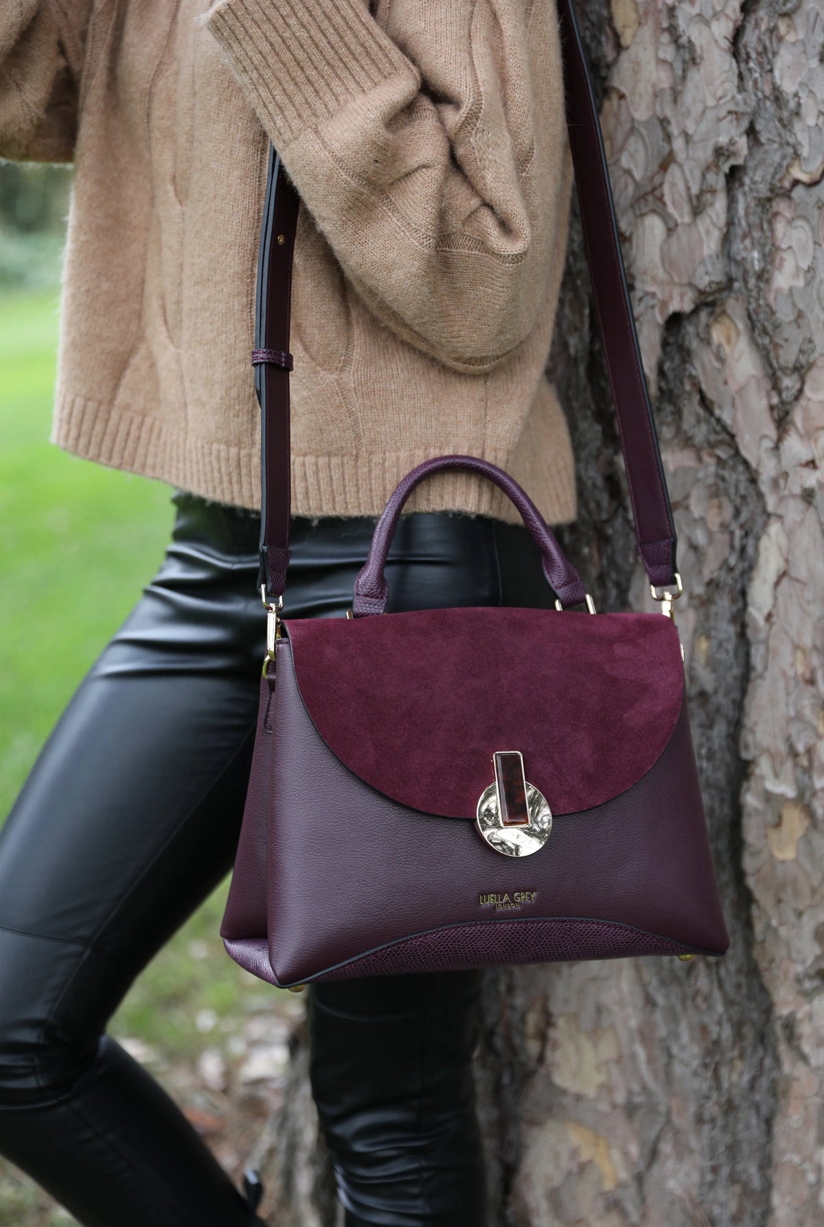 Purple leather-look handbag with curved flap and gold-tone clasp, front close-up