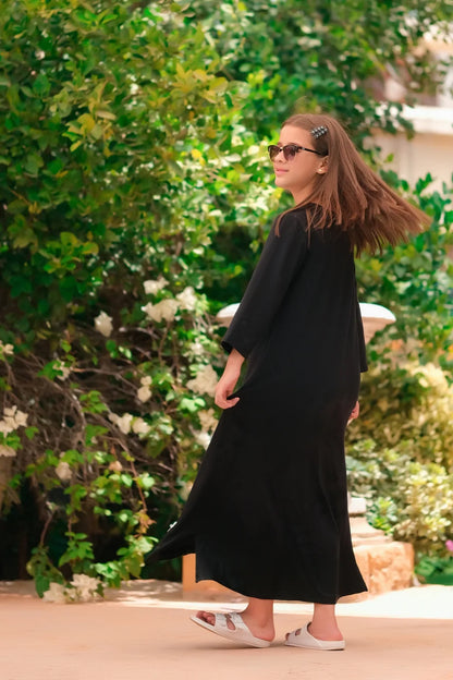 Black long-sleeve maxi dress with round neck and side slit, back three-quarter view