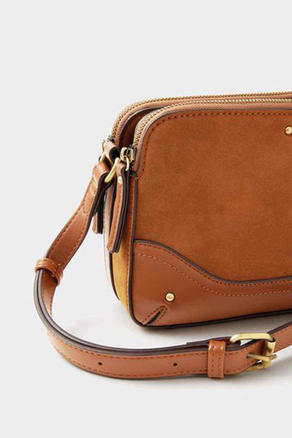 Tan crossbody bag with adjustable strap, gold buckles, and top zip