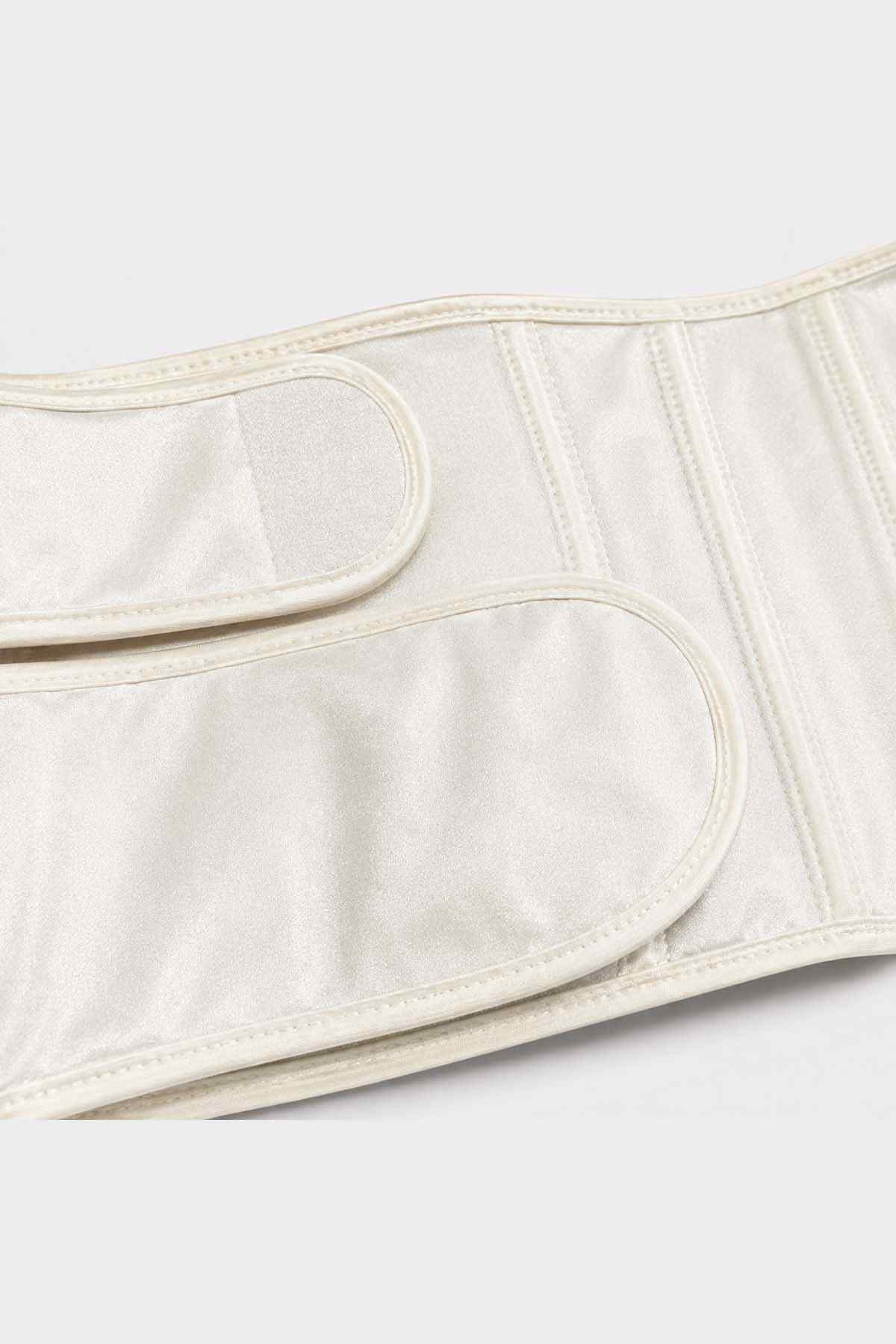 Cream belly band close-up with curved pocket seam and vertical stitching
