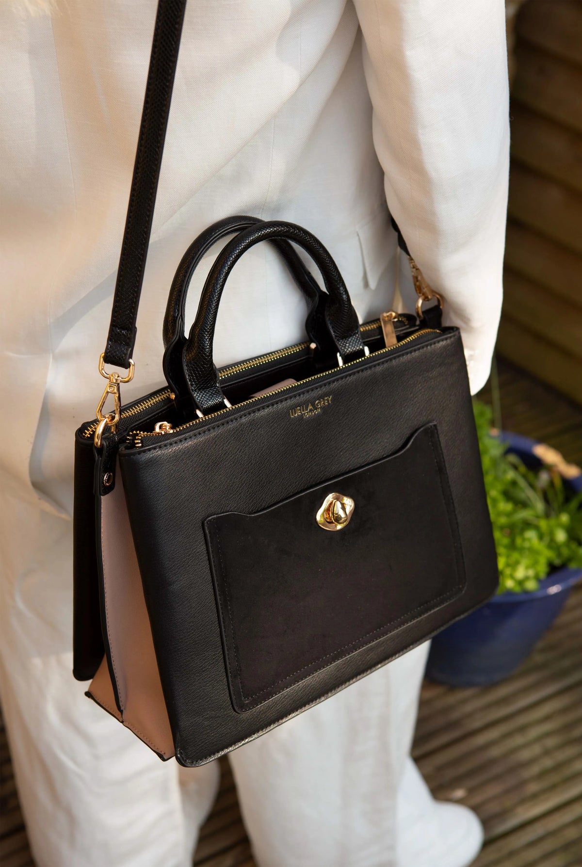 Black Luella Grey handbag side view with shoulder strap and front pocket detail