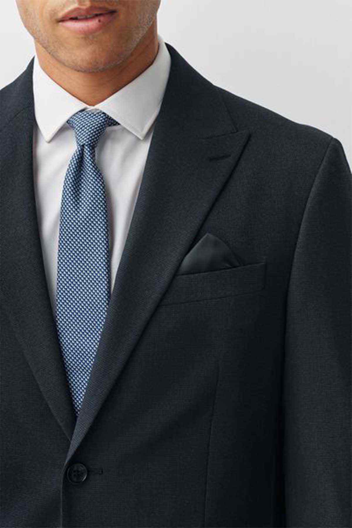 Navy suit jacket with notch lapel, pocket square, and buttoned front